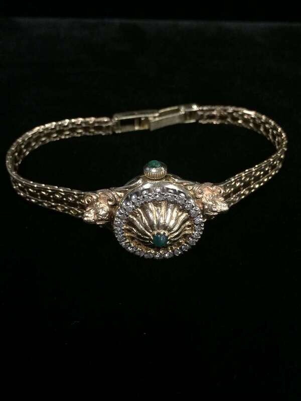 A diamond, emerald and fourteen karat gold covered dial